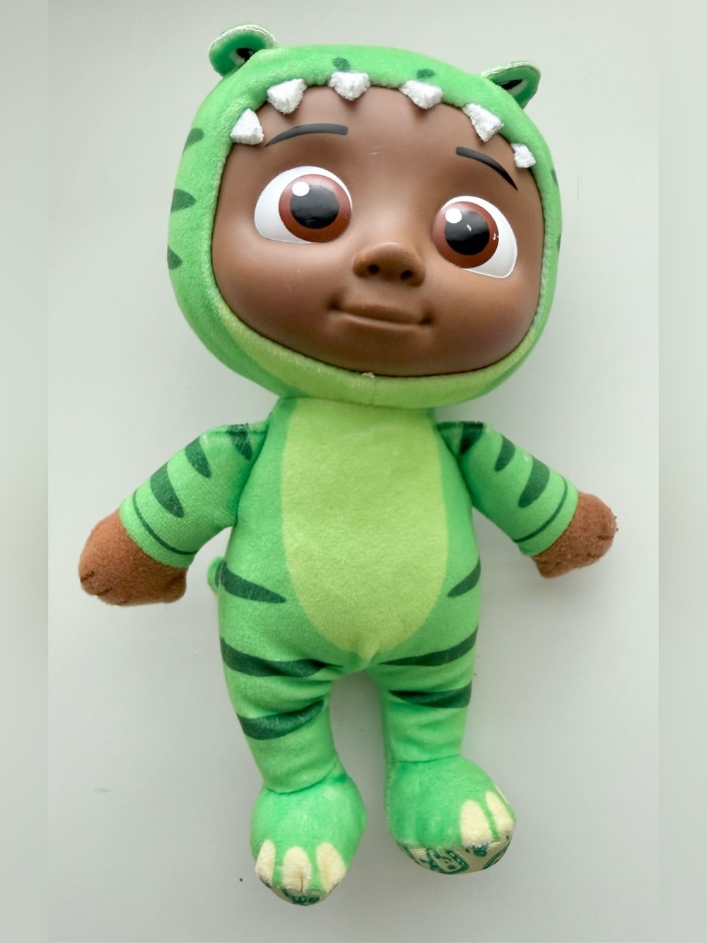 CoComelon Cody Little Plush character wearing a green dinosaur costume.
